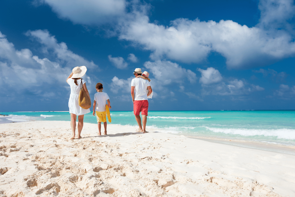 family on holidays walking along beach